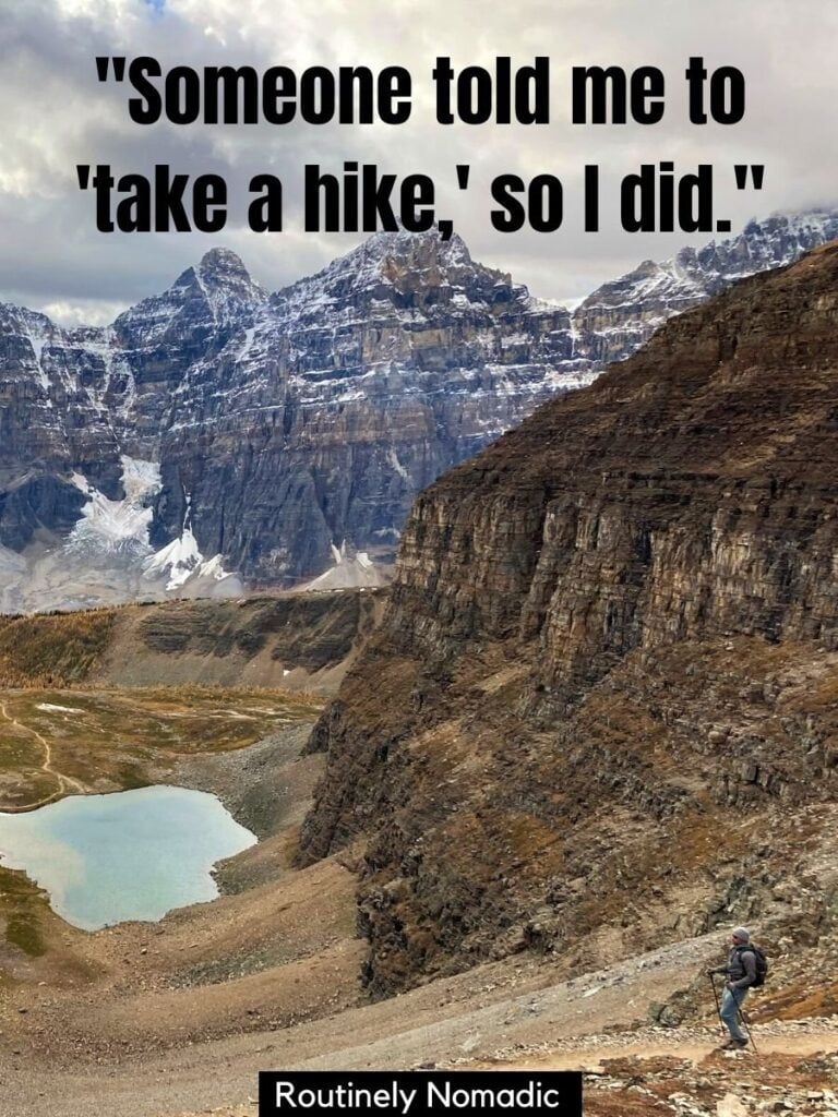 Person hiking with a lake and mountains behind and a funny hiking sayings that says someone told me to take a hike so I did
